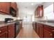 Galley kitchen featuring dark wood cabinets and black appliances with tile floors at 10847 Kirkwall Port Dr, Wimauma, FL 33598