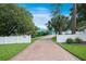 Long brick driveway leads to a beautiful home, set behind a white fence and lush landscaping at 1217 N Florida Ave, Tarpon Springs, FL 34689