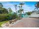 Charming home featuring lush landscaping with a rock water feature, a brick driveway, and colorful exterior at 1217 N Florida Ave, Tarpon Springs, FL 34689