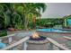 Cozy outdoor fire pit with Adirondack seating and lush tropical landscaping surrounding a beautiful pool at 1217 N Florida Ave, Tarpon Springs, FL 34689