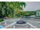 Relaxing fire pit area with built-in seating, nestled amidst tropical landscaping near the inviting pool at 1217 N Florida Ave, Tarpon Springs, FL 34689