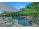 Beautiful pool area with lounge chairs, umbrellas, waterfall features, and surrounding greenery at 1217 N Florida Ave, Tarpon Springs, FL 34689
