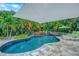Amazing backyard pool with lounge chairs, waterfall feature, and lush tropical landscaping at 1217 N Florida Ave, Tarpon Springs, FL 34689
