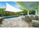 Luxurious outdoor pool area with a shade sail, waterfall feature, and ample patio space for entertaining at 1217 N Florida Ave, Tarpon Springs, FL 34689