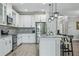 Modern kitchen with white cabinets, gray backsplash, granite countertops, stainless appliances, and island with seating at 12593 Retreat Pl, Spring Hill, FL 34610