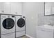 Well-equipped laundry room featuring modern washer and dryer, with a utility sink at 12593 Retreat Pl, Spring Hill, FL 34610