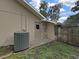 Side view of the house showing the back door, AC unit, and small yard area with partial wooden fence at 13094 Huntington Woods Ave, Spring Hill, FL 34609