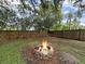 Cozy backyard fire pit area with stone surround, perfect for outdoor entertaining surrounded by wooden fence at 13094 Huntington Woods Ave, Spring Hill, FL 34609