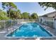Relaxing community pool surrounded by lush greenery, lounge chairs, and a secure fence for peace of mind at 13521 Forest Lake Dr, Largo, FL 33771