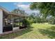 View of screened-in porch leading to grassy backyard with trees, offering a relaxing outdoor space at 1617 Dawnridge Ct, Brandon, FL 33510