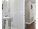 Powder room featuring a white pedestal sink, oval mirror, and hardwood floors at 18696 Malinche Loop, Spring Hill, FL 34610