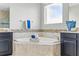 Well-lit bathroom with a corner soaking tub, dark cabinetry, and tiled walls at 18696 Malinche Loop, Spring Hill, FL 34610