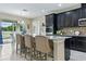 Modern kitchen featuring dark cabinets, stainless steel appliances, tile backsplash, and island seating at 18696 Malinche Loop, Spring Hill, FL 34610