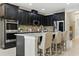 Modern kitchen featuring dark cabinets, stainless steel appliances, tile backsplash, and island seating at 18696 Malinche Loop, Spring Hill, FL 34610