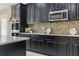 Modern kitchen featuring sleek black cabinets, stainless steel appliances, and a stylish mosaic backsplash at 18696 Malinche Loop, Spring Hill, FL 34610