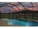 Beautiful pool with spa and patio under a screen enclosure at dusk at 18696 Malinche Loop, Spring Hill, FL 34610