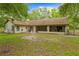 View of the home's back exterior, showing a large screened in porch and a spacious yard at 19555 Phillips Rd, Brooksville, FL 34604