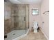Tiled shower with glass door, window, and toilet in updated bathroom at 19555 Phillips Rd, Brooksville, FL 34604
