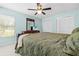 Bedroom with ceiling fan, tv on dresser, and large bed with green quilt at 19555 Phillips Rd, Brooksville, FL 34604