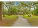 Home's front exterior with long driveway and mature trees in a landscaped lawn at 19555 Phillips Rd, Brooksville, FL 34604