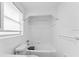 All white bathroom with tub, toilet, tiled walls, and window bringing in natural light at 2320 W Walnut St, Tampa, FL 33607