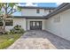 Close up of a home's exterior with gray double doors, a matching paved driveway, and manicured landscaping at 319 Midway Is, Clearwater Beach, FL 33767