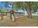 Back yard shows a playground with slide, concrete patio, and lush greenery and a large mature tree at 3619 15Th Se Ave, Largo, FL 33771