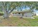 Back yard shows a patio with a place for a fire pit, back entrance to the home and large tree at 3619 15Th Se Ave, Largo, FL 33771