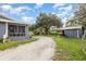 Gravel driveway leading to a charming house with a screened-in porch and a detached garage at 36725 Arcadia Ave, Myakka City, FL 34251