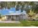 Exterior shot of a well-maintained home with metal roof, a screened porch, and mature landscaping at 36725 Arcadia Ave, Myakka City, FL 34251