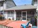 Exterior view of a screened-in porch and a brick patio with a blue chair at 39650 Us Hwy 19 N, Tarpon Springs, FL 34689