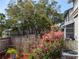 Fenced backyard showcasing mature trees and a blooming garden, offering a private outdoor space at 39650 Us Hwy 19 N, Tarpon Springs, FL 34689