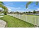 Landscaped backyard featuring a white picket fence and a serene pond view at 449 Bahama Grande Blvd, Apollo Beach, FL 33572