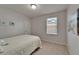 Cozy bedroom features neutral tones, a window with blinds, a comfortable bed with a white comforter, and light carpet at 449 Bahama Grande Blvd, Apollo Beach, FL 33572