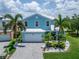 Charming two-story blue home with a paver driveway, lush landscaping, and a white garage door at 449 Bahama Grande Blvd, Apollo Beach, FL 33572