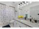 Well-lit bathroom with a granite countertop vanity, decorative mirror, and a shower with a stylish curtain at 5812 Blossom Ave, Tampa, FL 33614