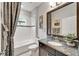 Well-lit bathroom with a granite vanity, shower-tub combo, tiled walls and decorative mirror at 6127 Colmar Pl, Apollo Beach, FL 33572