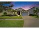 Charming single-Gathering home with well-manicured lawn and tropical landscaping at dusk at 6127 Colmar Pl, Apollo Beach, FL 33572