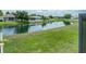 Scenic backyard pond view with lush green grass and houses in the background, creating a tranquil and inviting outdoor space at 6957 Boulder Run Loop, Wesley Chapel, FL 33545