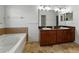 Bathroom with tiled floors, dual sinks, soaking tub, and cherry wood vanity cabinetry at 6957 Boulder Run Loop, Wesley Chapel, FL 33545