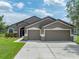 Charming single-story home featuring a three-car garage, stone accents and a well-manicured front lawn at 6957 Boulder Run Loop, Wesley Chapel, FL 33545