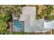 Aerial view of a home featuring a screened-in pool and a well-maintained gray shingle roof surrounded by lush landscaping at 7613 Bramblewood Dr, Port Richey, FL 34668