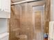 Bathroom featuring a glass-enclosed shower with brown tiling and updated fixtures at 7613 Bramblewood Dr, Port Richey, FL 34668