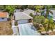 Exterior elevation showcasing stone accents, a two-car garage, mature trees, and an arched entry in a lush setting at 7613 Bramblewood Dr, Port Richey, FL 34668