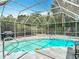 Inviting screened-in pool with clear blue water surrounded by lush greenery at 7613 Bramblewood Dr, Port Richey, FL 34668