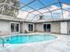 A screened-in pool area with a pool and an adjacent sitting area at 7613 Bramblewood Dr, Port Richey, FL 34668