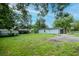 Large grassy backyard with mature trees and a shed in the background at 7702 New York Dr, Tampa, FL 33619