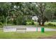 Community basketball court with hoops and benches, surrounded by trees at 7702 New York Dr, Tampa, FL 33619