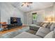Comfortable living room features a gray sectional sofa, balcony access, ceiling fan, and entertainment center at 820 Normandy Trace Rd, Tampa, FL 33602