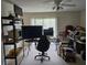 View of a living room with a ceiling fan, large windows, a desk, computers, and shelving at 9100 Mlk N St # 503, St Petersburg, FL 33702